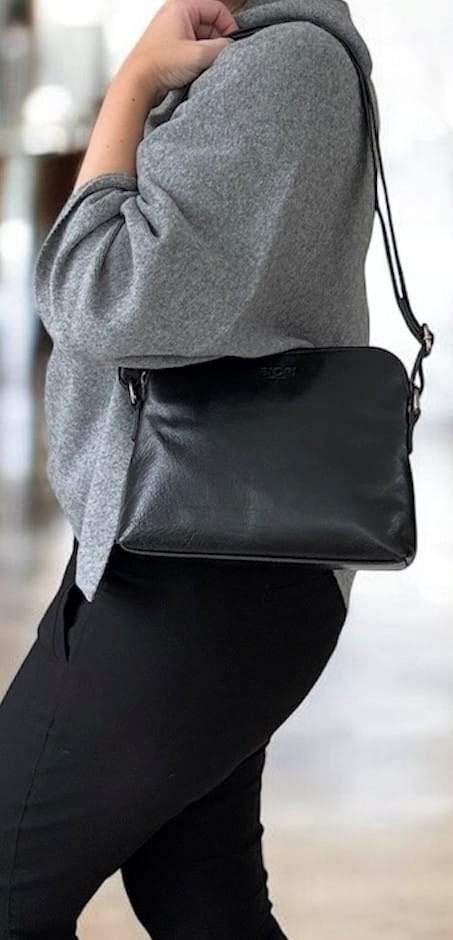 Framsida av svart läderväska från Biori Sweden med dragkedja i toppen och en justerbar axelrem, buren av modell