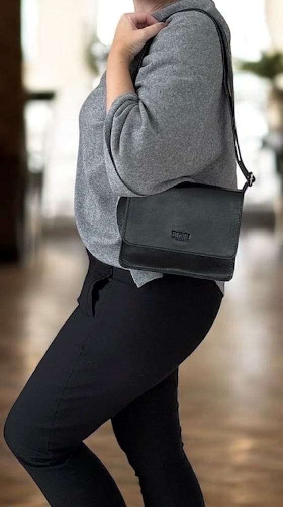 Handväska i svart skinn med rak klaff och justerbar axelrem från Biori Sweden, buren av modell